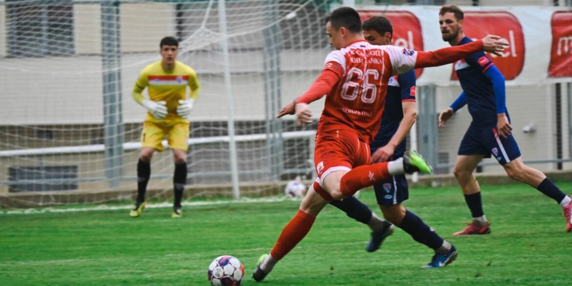 Fudbaler FK Sloboda u crvenom dresu sa brojem 66 šutira loptu – arhivska fotografija